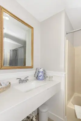 a white bathroom with a sink and a mirror at Brandywine River Hotel in Chadds Ford