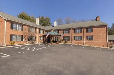 a large red brick building with a parking lot at Brandywine River Hotel in Chadds Ford