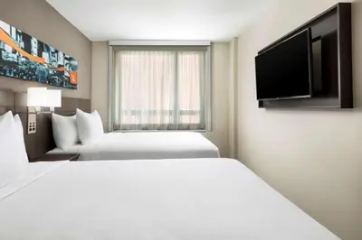 a hotel room with two beds and a flat screen tv at Hyatt Place New York City - Times Square in New York