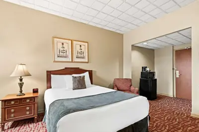 a hotel room with a large bed and a chair at Genetti Hotel, SureStay Collection by Best Western in Williamsport