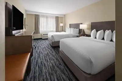 a hotel room with two beds and a flat screen tv at Penn Harris Hotel Harrisburg, Trademark by Wyndham in Harrisburg