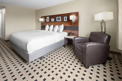 a hotel room with a bed and a chair at Penn Harris Hotel Harrisburg, Trademark by Wyndham in Harrisburg