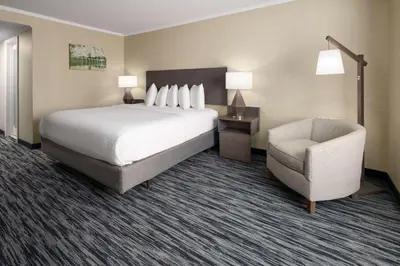 a hotel room with a bed and a chair at Penn Harris Hotel Harrisburg, Trademark by Wyndham in Harrisburg