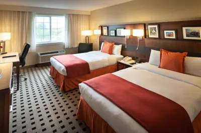 a hotel room with two beds and a desk at Penn Harris Hotel Harrisburg, Trademark by Wyndham in Harrisburg