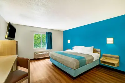 a hotel room with a bed and a blue wall at Motel 6-Gordonville, PA - Lancaster PA in Gordonville