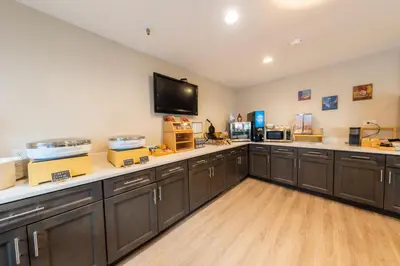 a large kitchen with brown cabinets and a flat screen tv at The Westfield Inn, BW Signature Collection in Westfield