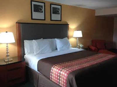 a hotel room with a bed and a chair and two lamps at Media Inn & Suites in Media