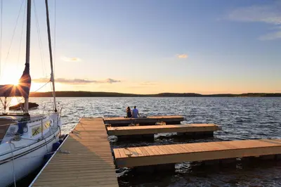 two people standing on a dock in the water with a boat at Silver Birches Resort in Hawley