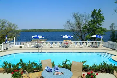 a swimming pool with chairs and a table and the water at Silver Birches Resort in Hawley