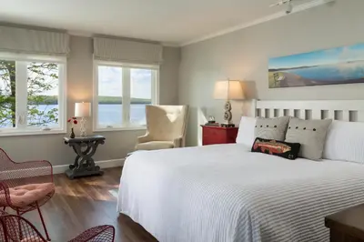 a bedroom with a bed and two chairs and windows at Silver Birches Resort in Hawley
