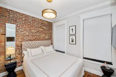 a bedroom with a white bed and a brick wall at APARTMENT NOLITA in New York