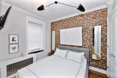 a bedroom with a white bed and a brick wall at APARTMENT NOLITA in New York