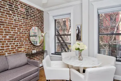 a living room with a brick wall and a table and chairs at APARTMENT NOLITA in New York