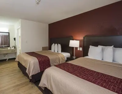 a hotel room with two beds and a lamp at Red Roof Inn Lancaster Strasburg in Lancaster