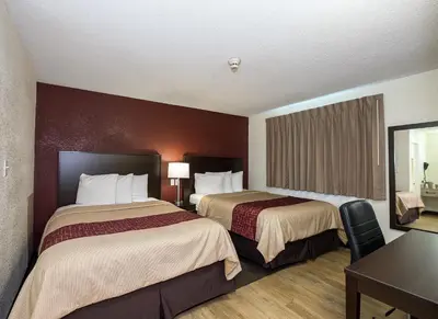 a hotel room with two beds and a table at Red Roof Inn Lancaster Strasburg in Lancaster