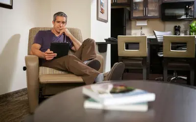 a man sitting in a chair in a room at Candlewood Suites Philadelphia - Airport Area by IHG in Chester