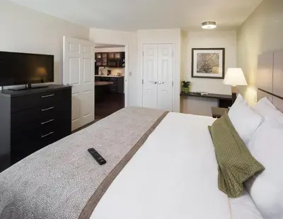 a bedroom with a large white bed with a television at Candlewood Suites Philadelphia - Airport Area by IHG in Chester