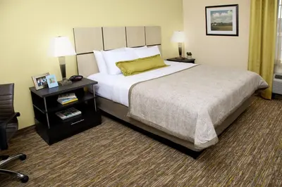 a hotel room with a large bed and a night stand at Candlewood Suites Philadelphia - Airport Area by IHG in Chester