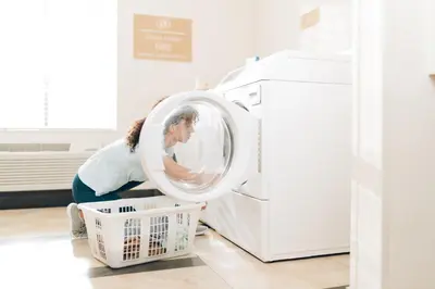 a woman loading a washing machine in a kitchen at Candlewood Suites Philadelphia - Airport Area by IHG in Chester