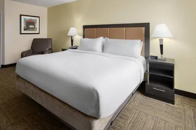a hotel room with a large bed and a chair at Candlewood Suites Philadelphia - Airport Area by IHG in Chester