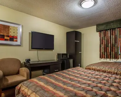 a hotel room with a bed and a desk and a tv at Rodeway Inn Belleville in Belleville