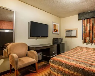 a hotel room with a bed and a desk and a television at Rodeway Inn Belleville in Belleville