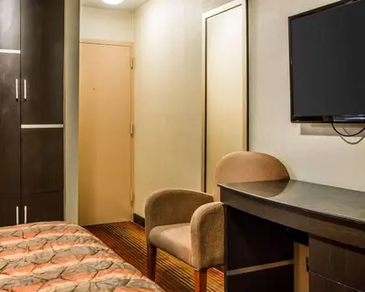 a hotel room with a bed and a desk and a tv at Rodeway Inn Belleville in Belleville