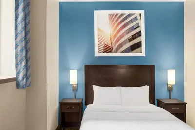 a bed in a hotel room with a blue wall at Days Inn by Wyndham Philadelphia Convention Center in Philadelphia
