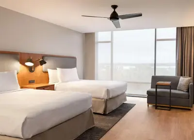 a hotel room with two beds and a chair and a window at Homewood Suites By Hilton Wilmington Downtown in Wilmington