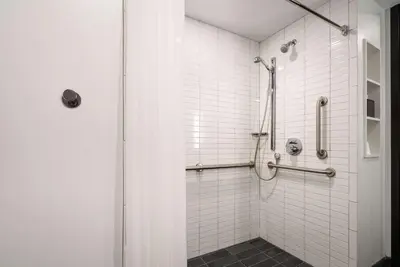 a bathroom with a shower with white tiles at Motto by Hilton Philadelphia Rittenhouse Square in Philadelphia