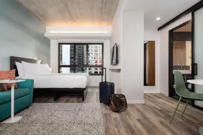 a hotel room with a bed and a suitcase at Motto by Hilton Philadelphia Rittenhouse Square in Philadelphia