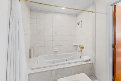 a white bath tub in a white tiled bathroom at Penn's View Hotel Philadelphia in Philadelphia