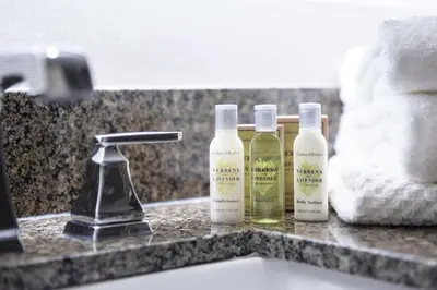 three bottles of moisturizers sitting on a bathroom sink at The Desmond Hotel Malvern, a DoubleTree by Hilton in Malvern