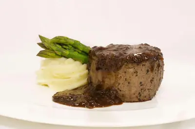 a piece of meat and vegetables on a white plate at The Desmond Hotel Malvern, a DoubleTree by Hilton in Malvern