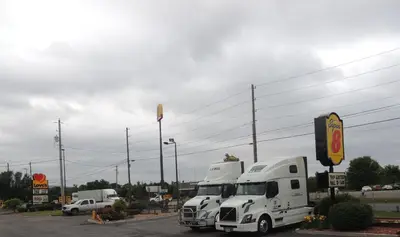 two white semi trucks parked in a parking lot at Super 8 by Wyndham Mifflinville Near Bloomsburg in Mifflinville