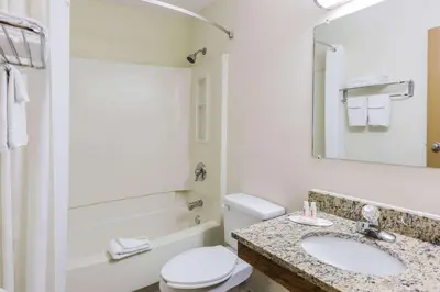 a bathroom with a sink and a toilet and a mirror at Super 8 by Wyndham East Stroudsburg - Poconos in East Stroudsburg