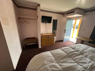 a bedroom with a white bed and a television at Mark Twain Motor Inn in Elmira