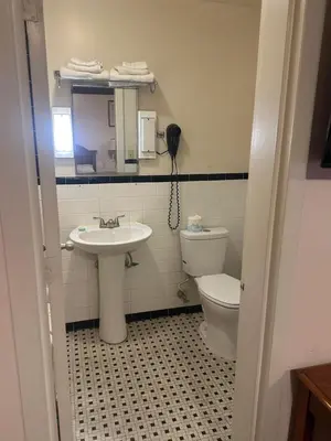 a bathroom with a sink and a toilet and a phone at Mark Twain Motor Inn in Elmira