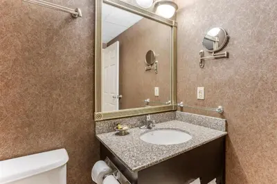 a bathroom with a sink and a mirror and a toilet at Best Western PLUS Morristown Inn-Florham Park in Morristown