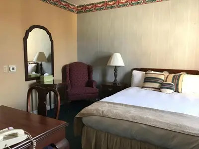 a hotel room with a bed and a chair and a mirror at Waynebrook Inn in Honey Brook