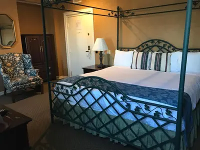 a bedroom with a canopy bed and a chair at Waynebrook Inn in Honey Brook