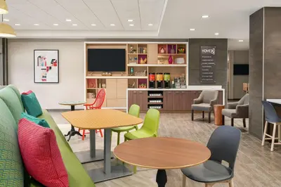a waiting room with tables and chairs and a tv at Home2 Suites By Hilton Harrisburg Hershey in Harrisburg