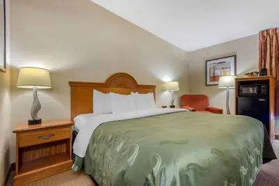 a hotel room with a large bed and a chair at Quality Inn & Suites Mansfield in Mansfield