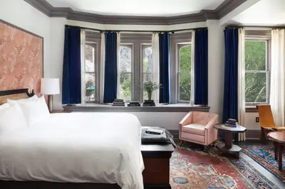 a bedroom with a bed and a chair and windows at The High Line Hotel in New York
