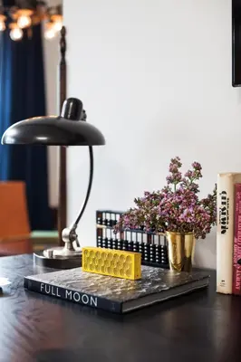 a book with full moon on a desk with a lamp and flowers at The High Line Hotel in New York