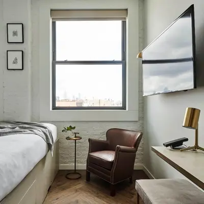 a bedroom with a bed and a chair and a window at Walker Hotel Tribeca in New York