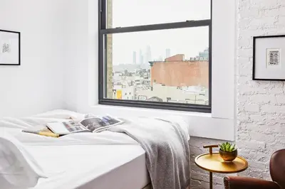 a bedroom with a bed and a large window at Walker Hotel Tribeca in New York