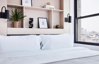 a white bedroom with white pillows and a window at Walker Hotel Tribeca in New York