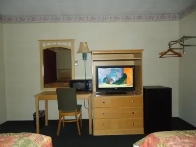 a hotel room with a television on a dresser with a desk at Relax Inn in Fisherville