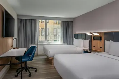 a hotel room with two beds and a desk at Courtyard by Marriott Times Square West in New York